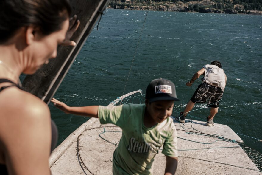 The blurred side of the woman as she watches a child wearing a green shirt and baseball cap, 