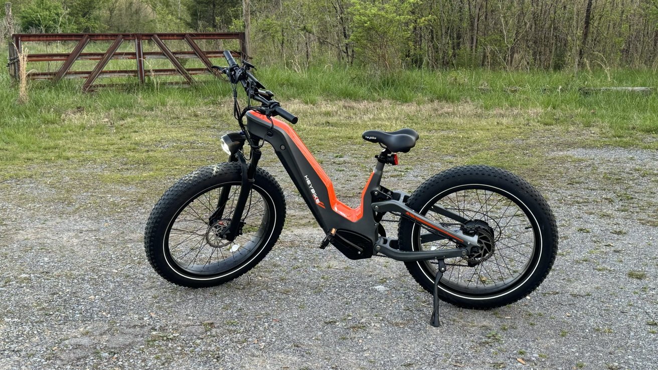 Heybike Hero on a gravel path with wilderness and an old gate in the background