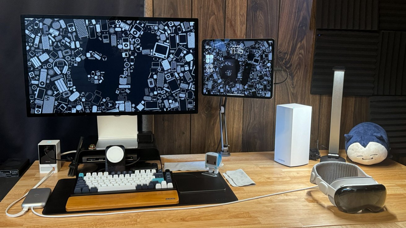 A desk setup showing the previous iPad Pro in a magnetic stand that makes it float above the desk. It sits next to a Studio Display and various computing accessories.