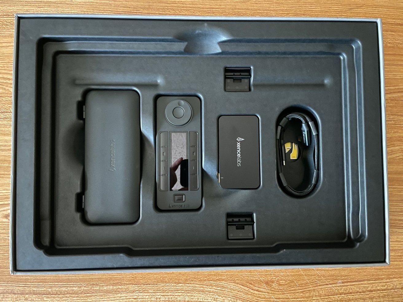 Box with a stylus, pen holder, charging cable, and accessories placed in a black foam insert.