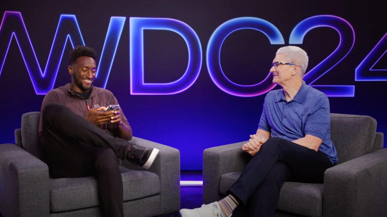 Two men seated in armchairs, one smiling at his phone, the other looking at him, with 'WWDC24' glowing text in the background.