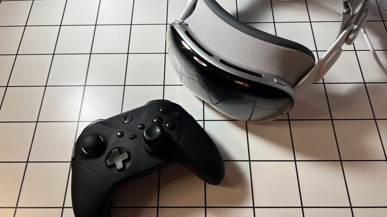 Black game controller and Apple Vision Pro on a white grid-patterned surface.