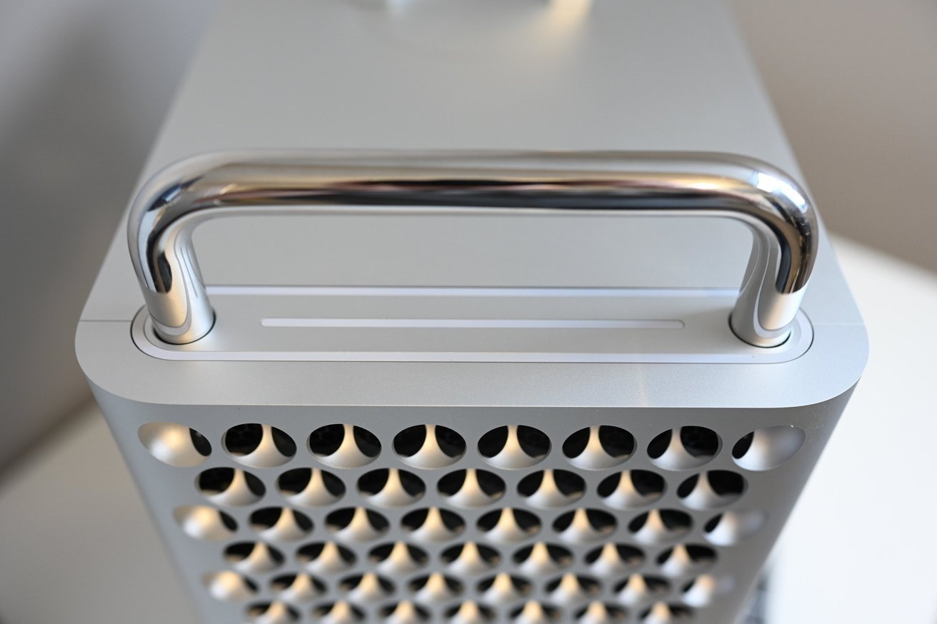 Silver computer tower with rounded edges, a perforated front panel, and a shiny, curved handle on top.