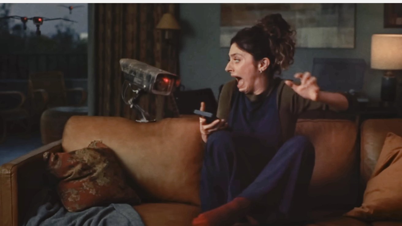 Woman on couch, holding remote, screams at hovering robot with cameras; drones outside window.