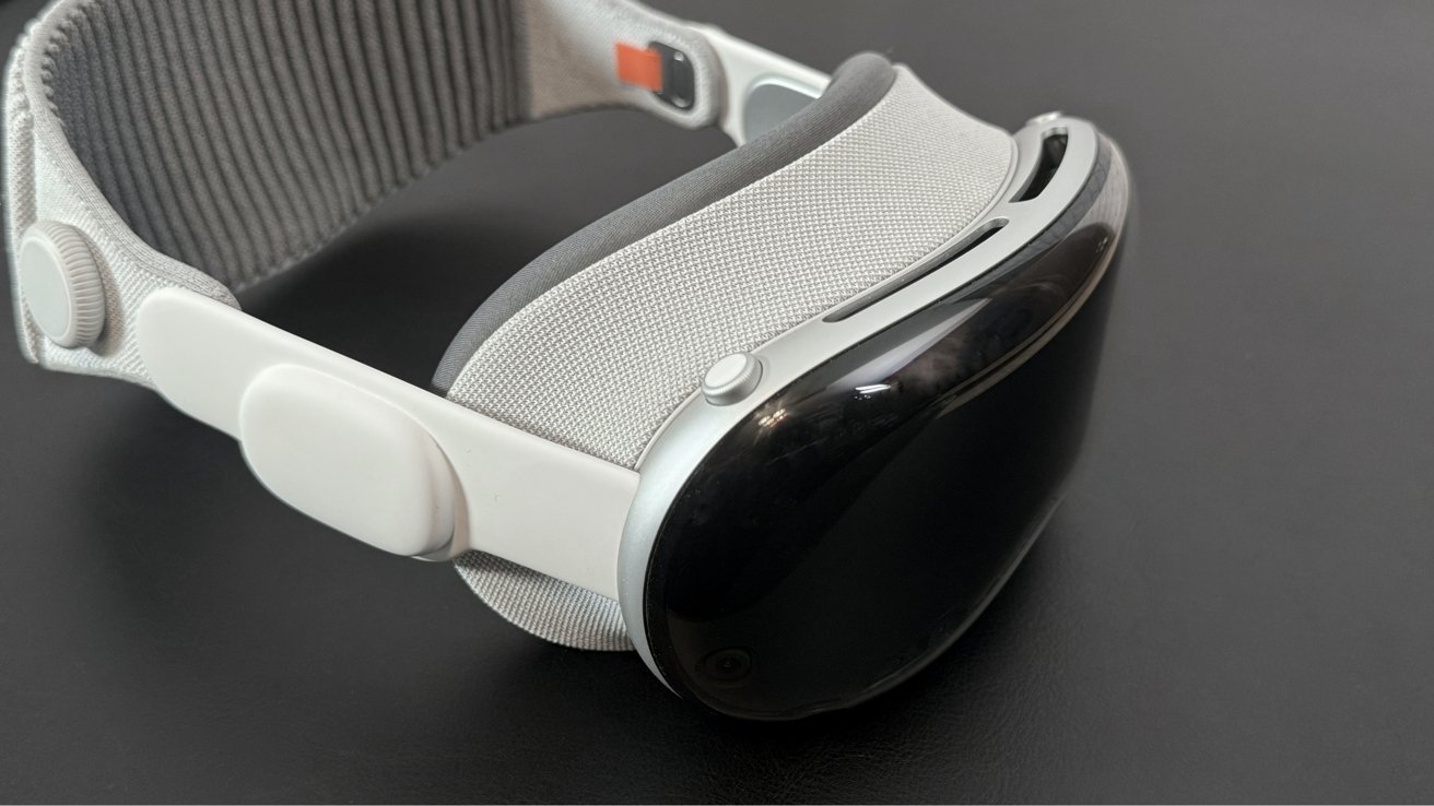 An Apple Vision Pro headset with a sleek design, featuring a black visor, white frame, and adjustable fabric strap.