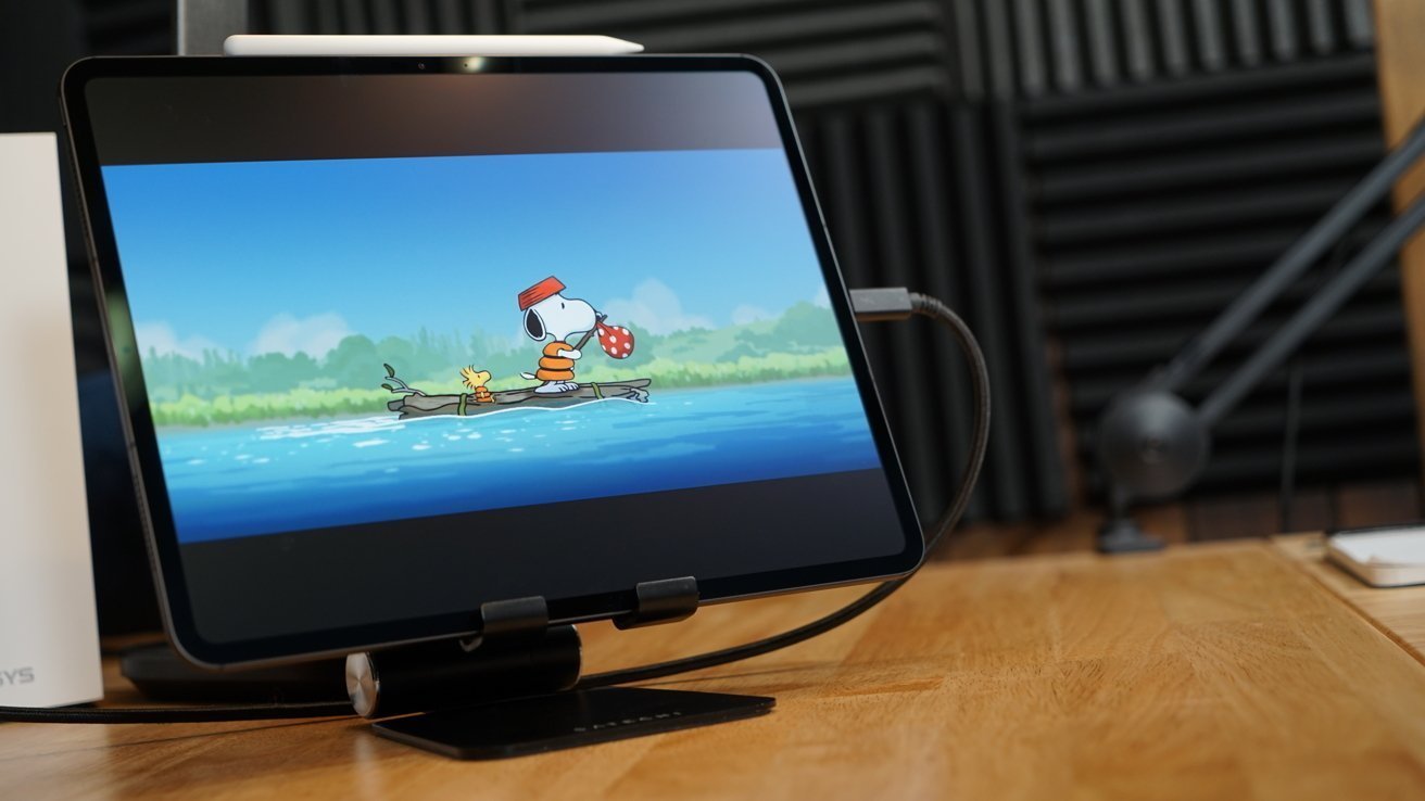 M4 iPad Pro 13-inch on a wooden desk displaying Snoopy and Woodstock characters on screen.