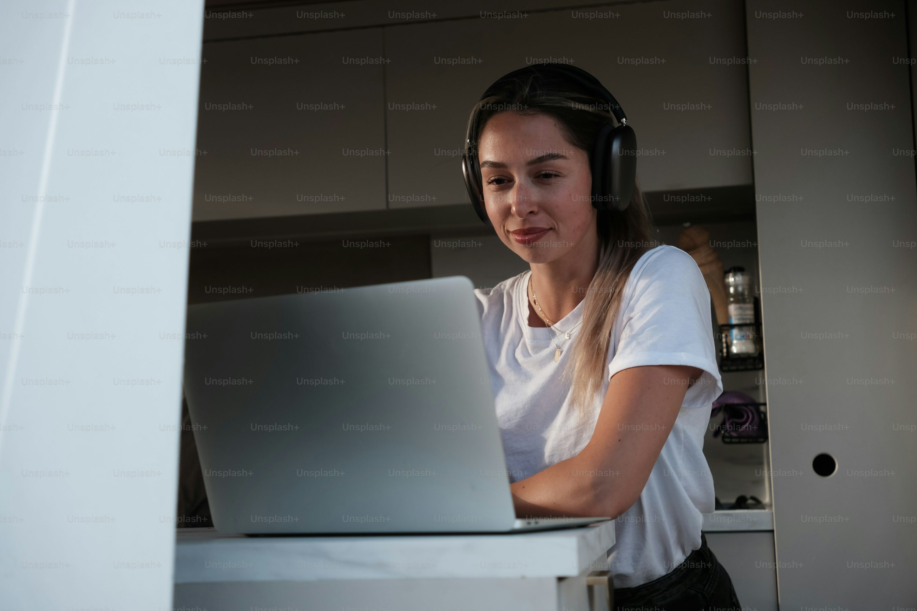 Una mujer con auriculares mirando una computadora portátil