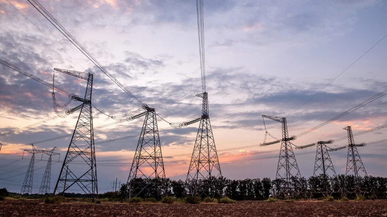 Electrical pylons and high voltage power lines at sunset background. Group silhouette of transmission towers. critical infrastructure