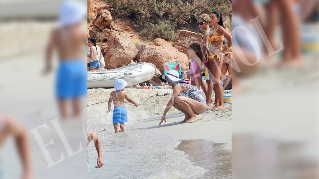 Xisca Perelló, jugando su hijo en la orilla de la cala.