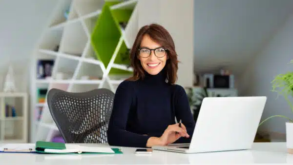 smiling-business-woman-glasses-laptop-desk-ss-1920