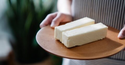 image of two sticks of margarine on wood plate held by two hands, history of margarine