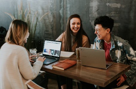 This is an image of three woman behind laptops sitting at an office