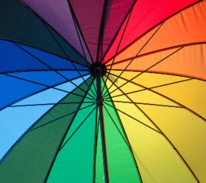 This is an image of a multicoloured umbrella, from the position of standing underneath the umbrella