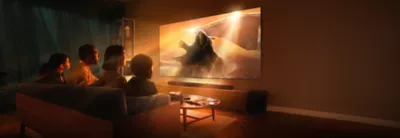 Living room scene with four people sitting on a sofa and wall-mounted TV and soundbar with screenshot of astronaut stepping through orange mist