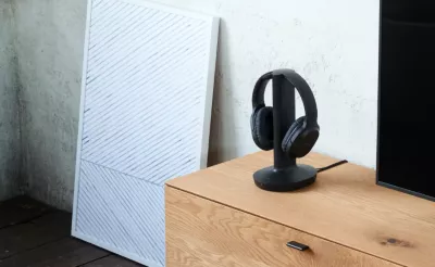 Lifestyle shot of in-home wireless headphones on a wooden console in a modern living room