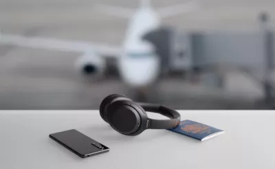 Black headband headphones sit on a grey desk next to two notepads