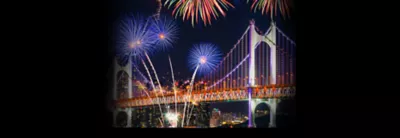 A fireworks display over a bridge at night