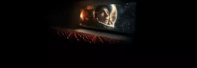 Cinema with red seats in foreground and screen showing movie of astronaut in space