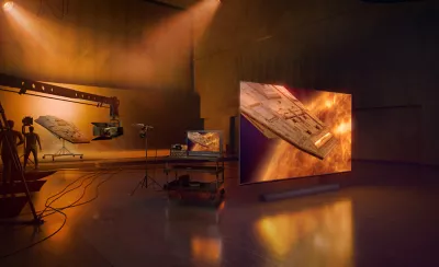 Studio scene with silhouette of technicians and production editing equipment to left and angled view of TV and soundbar to right with screenshot of spaceship in a misty red and blue environment