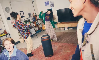 Image of four people in a living room dancing around the SRS-XV800 speaker with red ambient lighting 