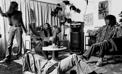 Black and white image of young people at a party with an ULT TOWER 10 speaker providing the music.