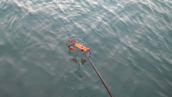 流れた電気ウキを網ですくう