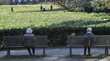 Due donne anziane siedono sulle panchine di un parco in Germania nel 2020