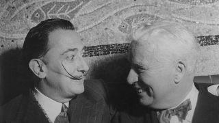 Salvador Dali sitting with Charlie Chaplin