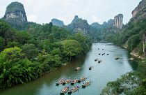 Turisti su zattere di bambù percorrono il fiume Jiuqu in un'area panoramica della montagna Wuyi, nella provincia sudorientale cinese del Fujian, il 3 ottobre 2023.