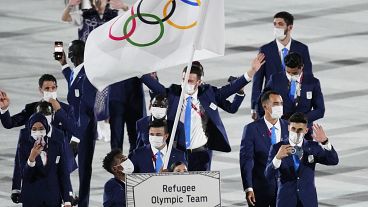 Yusra Mardini e Tachlowini Gabriyesos, da Equipa Olímpica de Refugiados, transportam a bandeira olímpica durante a cerimónia de abertura no Estádio Olímpico nos Jogos Olímpicos de verão de 2020.