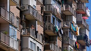 Una donna stende i panni ad asciugare sul balcone di un edificio residenziale a Madrid, in Spagna.