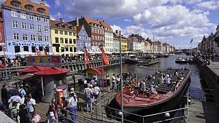 Turistas embarcam num ferry turístico na zona histórica do porto de Nyhavn, em Copenhaga, Dinamarca, no domingo, 28 de julho de 2024.