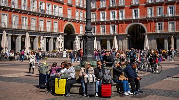 Turisti seduti su una panchina pubblica in Plaza Mayor, nel centro di Madrid (29 aprile 2024)