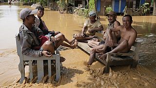 Residentes locales sentados en un banco en una carretera inundada en Naypyitaw, Myanmar, sábado 14 de septiembre de 2024.