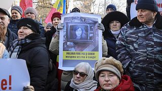 Una donna regge uno striscione raffigurante il presidente del Paese, Maia Sandu, con la scritta "Moldova senza PAS e Sandu" durante una protesta a Chisinau, in Moldova, giovedì 1 febbraio 2024.