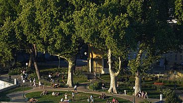 Personas disfrutan de una tarde de verano al aire libre en un jardín público de Lisboa en 2022.