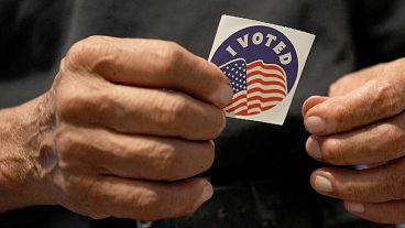 Carlos Salas, de 78 años, que recientemente se convirtió en ciudadano estadounidense y votó en sus primeras elecciones, sostiene una pegatina de "Yo voté" en su estudio en Alamo, TX, 3 de noviembre de 2024.