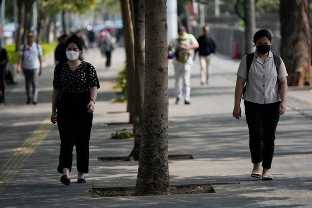 <p>People wear masks as they walk along a street in Jakarta city, Indonesia </p>