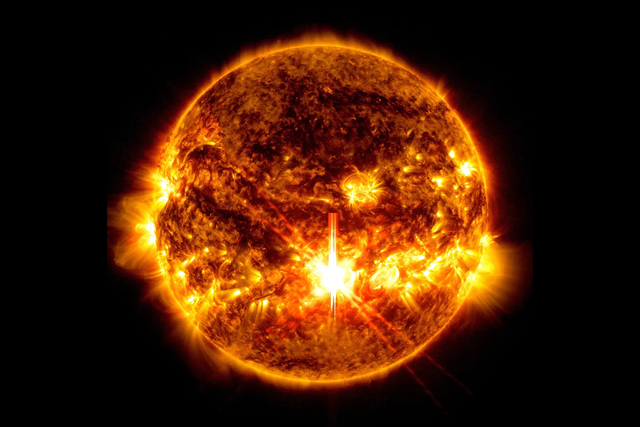 <p>NASA’s Solar Dynamics Observatory captured this image of a solar flare — seen as the bright flash in the center – on Oct. 3, 2024. The image shows subsets of extreme ultraviolet light that highlight the extremely hot material in flares and which are colorized in red and gold</p>