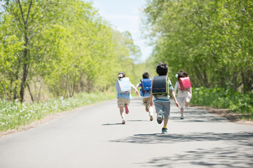 一本道を走る小学生の後姿