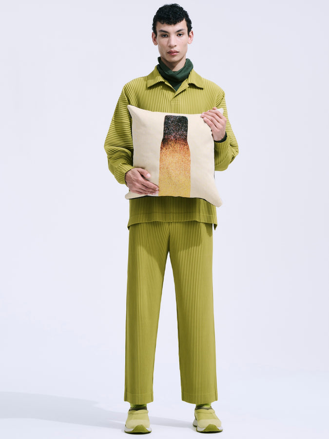 Model wearing a green suit and holding a printed tote bag.