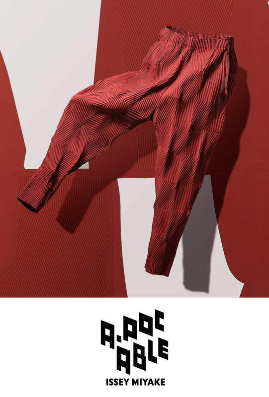 Top: TYPE-W 009 trousers in Dark Orange suspended mid-air. Background: A white sheet of trouser patten against red background. Bottom: A-POC ABLE ISSEY MIYAKE logo in black on white background.