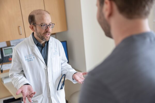 Physician Bill Wood meets with a patient in a clinic exam room.