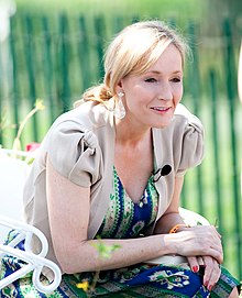 J. K. Rowling, author of Harry Potter and the Half-Blood Prince, crouches. She is wearing a blue dress under a grey jacket.