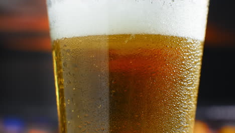 close-up slow motion: cold beer in a glass large drops and bubbles in the beer