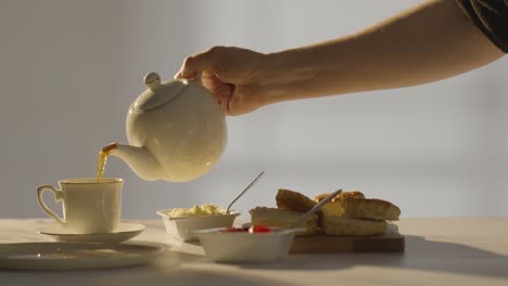 studio shot of person with traditional british afternoon tea with scones cream and jam 2