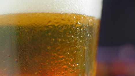 macro shot of a beer glass with cold beer bubbles rise in the glass. slow motion beer bubbles