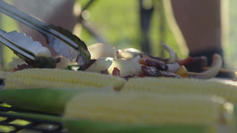 turning over skewers on a bbq with vegetables in the foreground