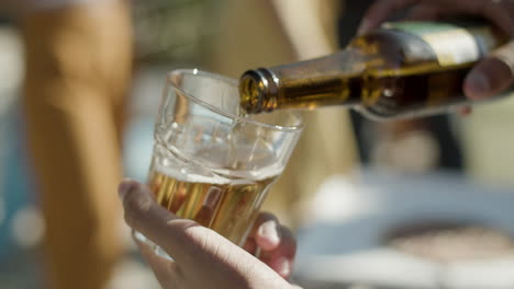 close up shot of an unrecognizable man holding glass in hand and pouring beer into it