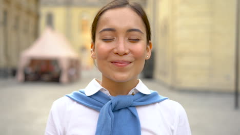 portrait of cheerful asian woman taking off her medical mask and taking a deep breath outdoors after coronavirus lockdown. covid-19 pandemic.